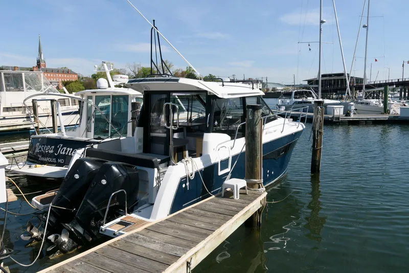 Slide: The Image of 2019 Jeanneau NC 895 boat docked in a marina, featuring sleek design and dual outboard engines. - 1
