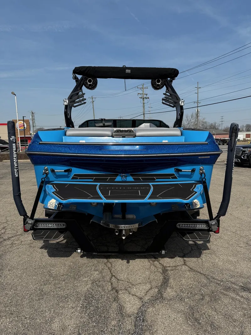 Slide: The Image of 2022 Centurion Fi23 boat, blue exterior, rear view, parked on pavement under clear sky. - 13