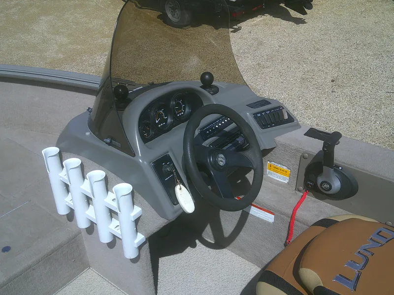 Slide: The Image of 2006 Lund 1600 Explorer SS boat dashboard with steering wheel and rod holders. - 12