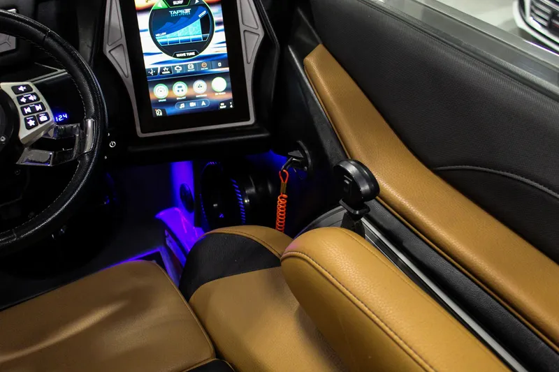 Slide: The Image of 2021 Tigé 25ZX boat interior with touchscreen controls and tan leather seats. - 16