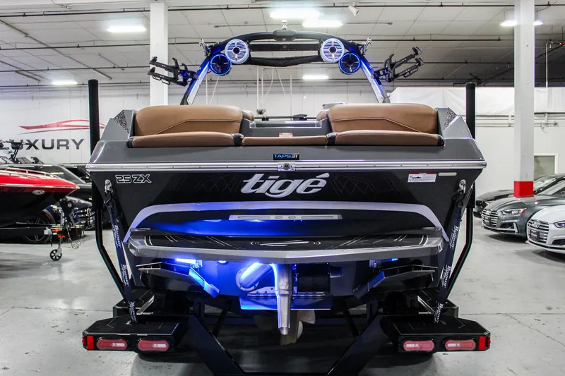 Slide: The Image of 2021 Tigé 25ZX boat with illuminated transom in a showroom setting. - 5