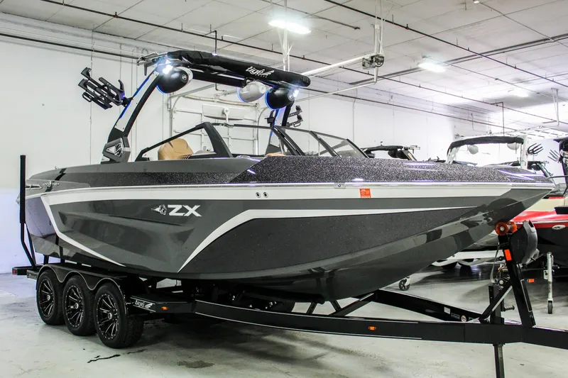 Slide: The Image of 2021 Tigé 25ZX boat in showroom, sleek design, black and gray color, on trailer. - 6