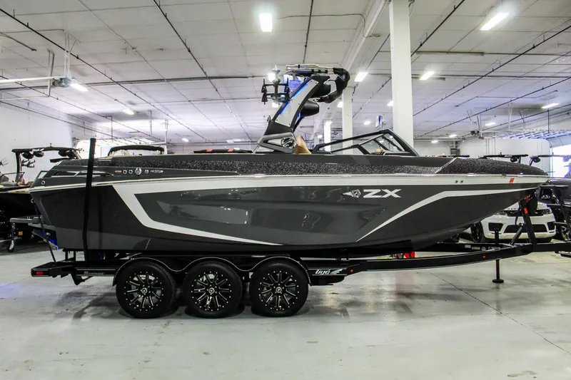 Slide: The Image of 2021 Tigé 25ZX boat in showroom, sleek design, triple-axle trailer, modern wakeboard tower. - 8