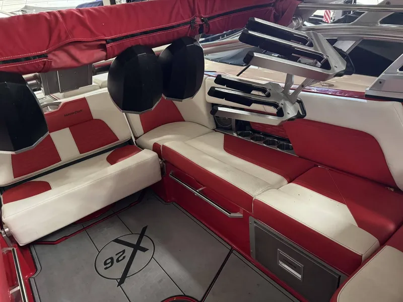 Slide: The Image of 2020 MasterCraft X26 boat interior with red and white seating, cup holders, and storage compartments. - 6