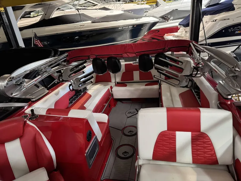 Slide: The Image of 2020 MasterCraft X26 boat interior with red and white seating, docked among other boats. - 7