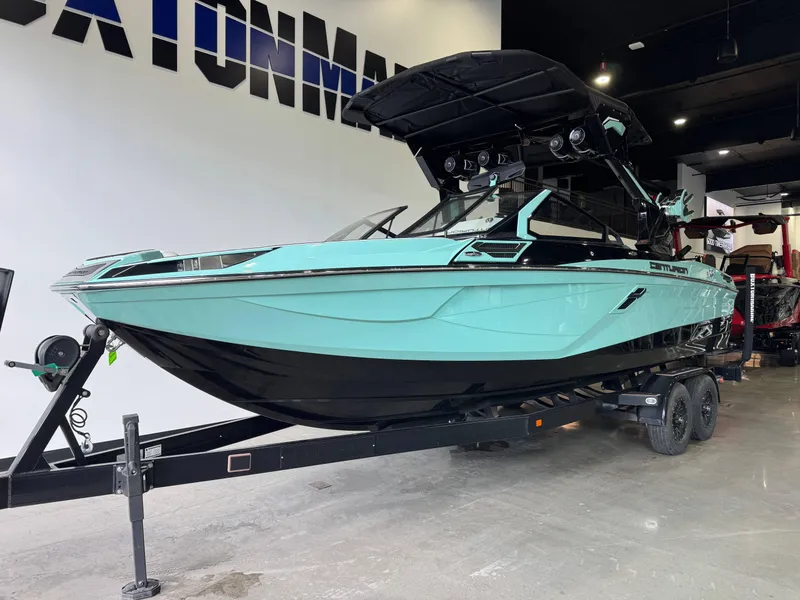 Slide: The Image of 2024 Centurion RI 245 boat in showroom, mint green and black design, on a trailer. - 2