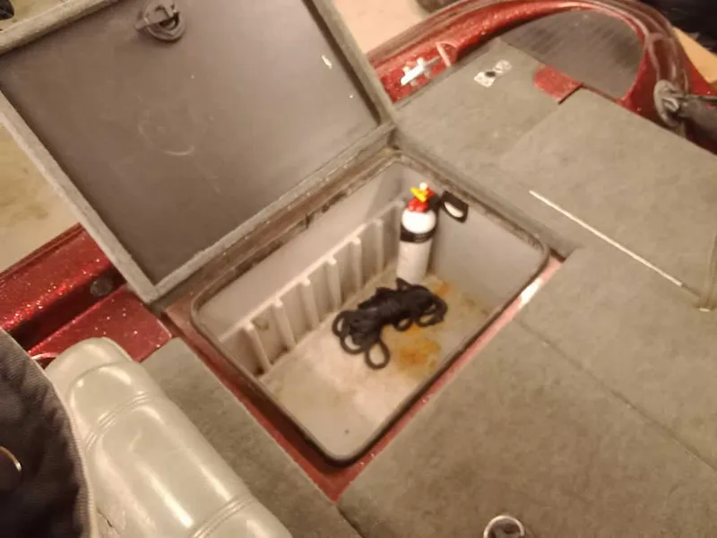 Slide: The Image of Open storage compartment in 2001 Triton TR186 sc boat with fire extinguisher and rope. - 29