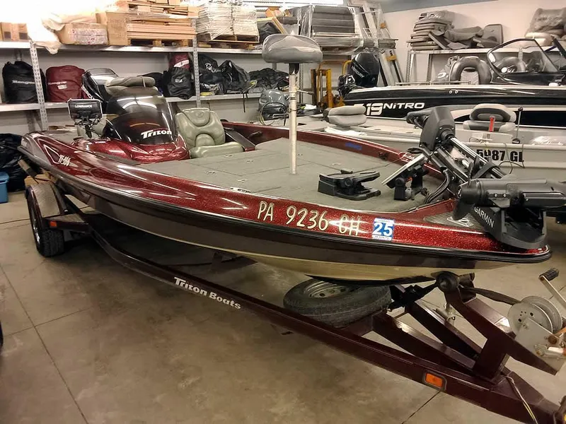 Slide: The Image of 2001 Triton TR186 SC bass boat in a garage, maroon color, on a trailer. - 32