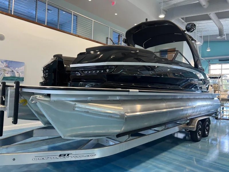 Slide: The Image of 2024 Veranda V One 25 pontoon boat displayed indoors on a trailer. - 2