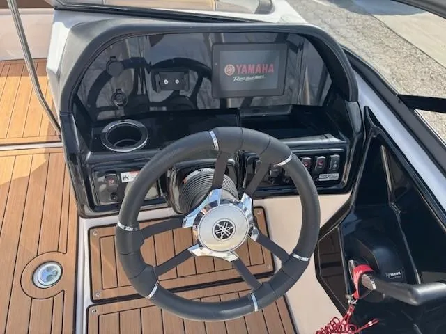 Slide: The Image of Steering wheel and dashboard of 2022 Yamaha Boats 195S, featuring modern controls and wood accents. - 16