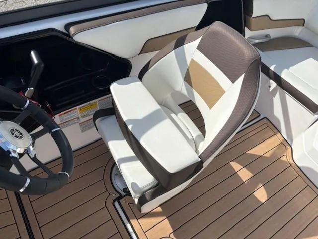 Slide: The Image of Captain's seat and steering wheel of 2022 Yamaha Boats 195S, featuring stylish upholstery and wood-like flooring. - 19