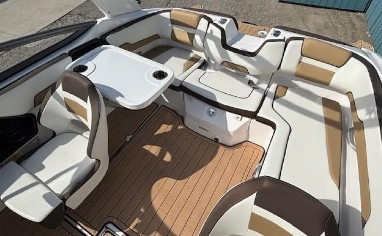 Slide: The Image of 2022 Yamaha Boats 195S interior with white and tan seating, table, and wood-style flooring. - 21