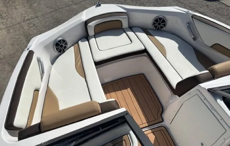 Slide: The Image of 2022 Yamaha Boats 195S interior with white and tan seating, teak flooring, and speakers. - 8