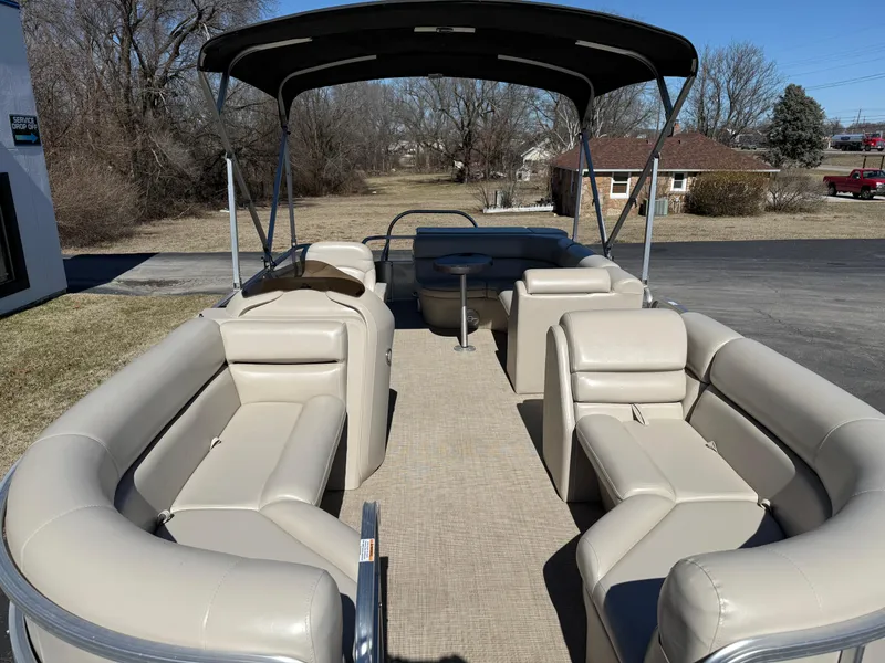 Slide: The Image of 2019 South Bay 222CR pontoon boat with beige seating and canopy, parked outdoors. - 5