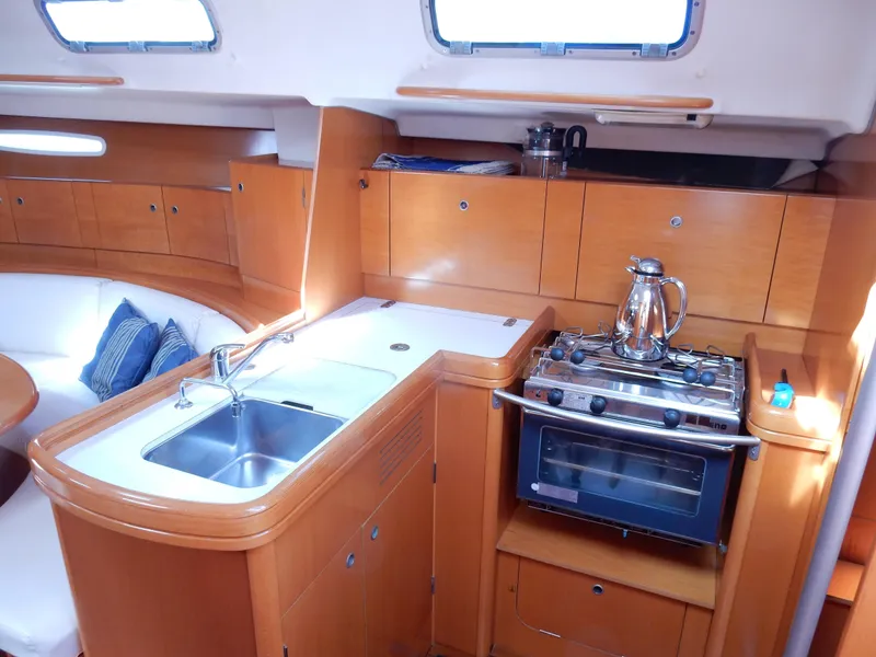 Slide: The Image of Interior of 2005 Beneteau First 44.7 yacht, featuring a compact kitchen with stove and sink. - 12