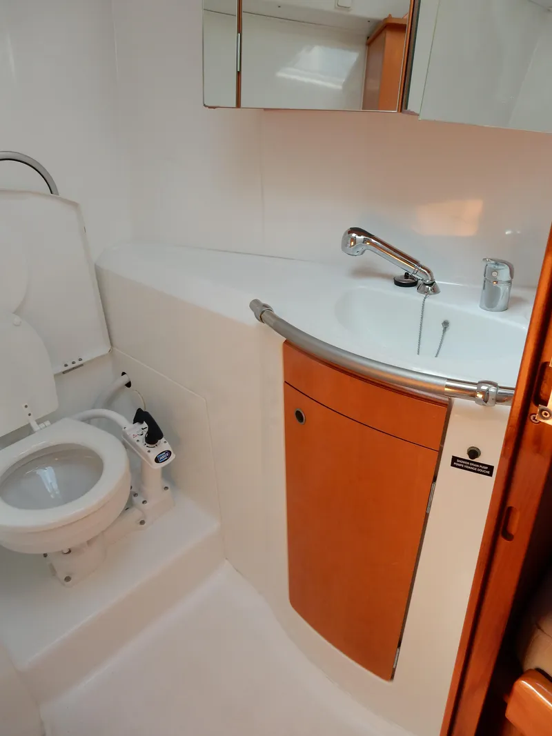 Slide: The Image of 2005 Beneteau First 44.7 yacht bathroom with sink, toilet, and wooden cabinetry. - 14