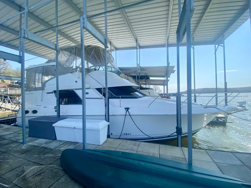 Slide: The Image of 1999 Silverton 392 Motor Yacht docked under a covered marina on a sunny day. - 1