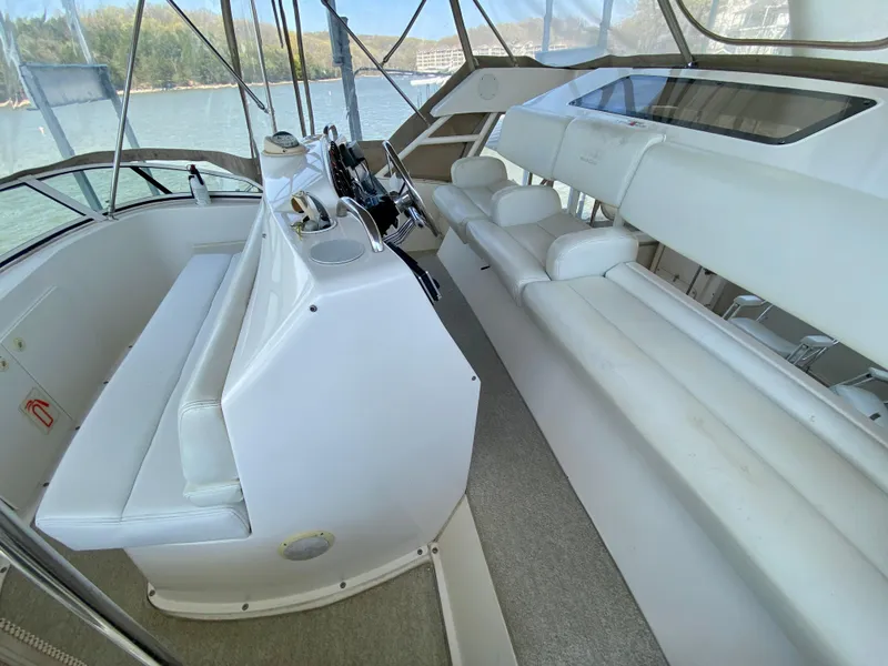 Slide: The Image of 1999 Silverton 392 Motor Yacht interior with white seating and helm, overlooking water. - 19