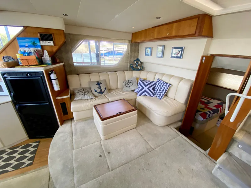 Slide: The Image of 1999 Silverton 392 Motor Yacht interior with beige seating, nautical decor, and cozy cabin space. - 21