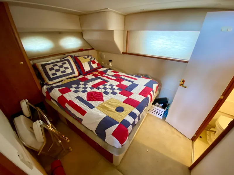 Slide: The Image of 1999 Silverton 392 Motor Yacht bedroom with nautical-themed bedding and cozy interior. - 32