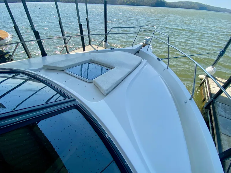 Slide: The Image of 1999 Silverton 392 Motor Yacht on calm water, showcasing sleek deck design and railing. - 6