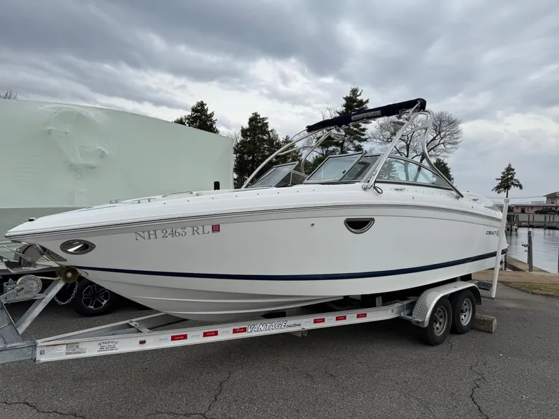 Slide: The Image of 2013 Cobalt 242 boat on trailer, parked outdoors under cloudy sky. - 0