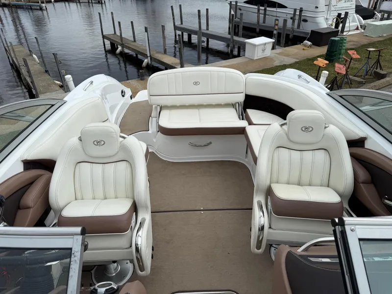 Slide: The Image of 2013 Cobalt 242 boat interior with white and brown seating, docked by a marina. - 12