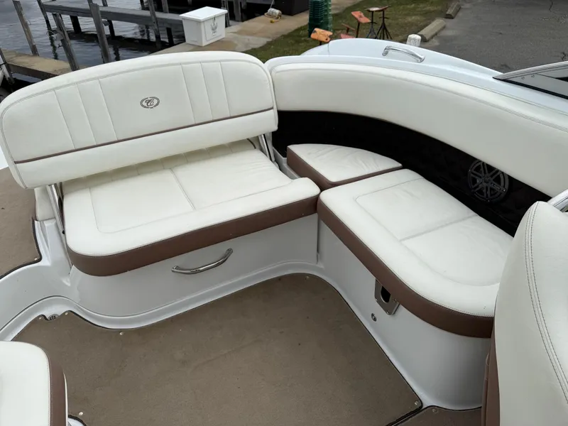 Slide: The Image of 2013 Cobalt 242 boat interior with white and brown seating near a dock. - 16