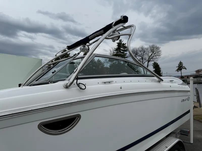 Slide: The Image of 2013 Cobalt 242 boat with sleek design and stainless steel features under cloudy sky. - 2