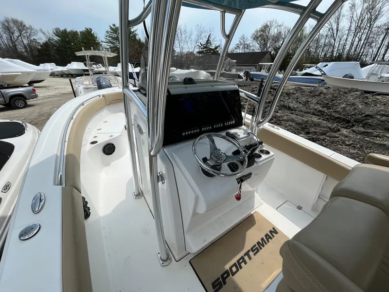 Slide: The Image of 2017 Sportsman 252 boat interior with steering console and seating, parked outdoors. - 11