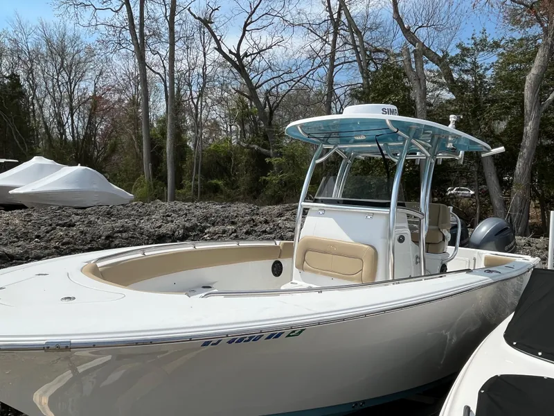 Slide: The Image of 2017 Sportsman 252 boat with T-top, parked outdoors near trees. - 2