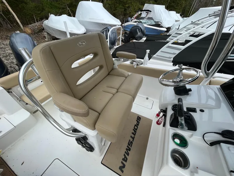 Slide: The Image of 2017 Sportsman 252 boat interior with beige seating and steering wheel, docked among covered boats. - 23
