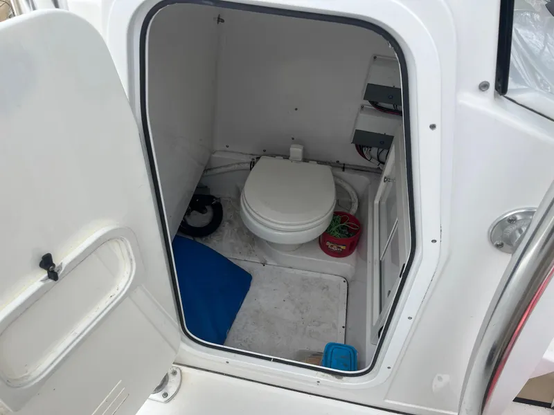 Slide: The Image of Boat bathroom interior on a 2017 Sportsman 252 model, featuring a compact toilet and storage. - 29