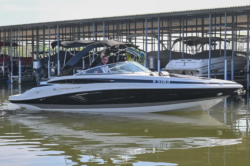 The Image of 2021 Crownline 265 SS boat docked in a marina, featuring sleek black and white design. - 1