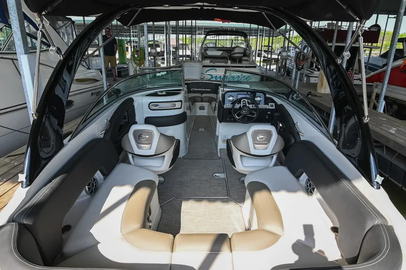 Slide: The Image of 2021 Crownline 265 SS boat interior with seating and dashboard in a marina setting. - 9