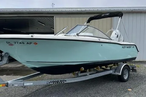 Slide: The Image of 2024 Key West 203 DFS boat on trailer, parked outside a storage building. - 0