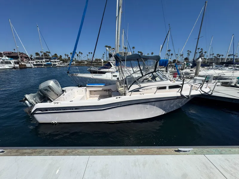 Slide: The Image of 1996 Grady-White Voyager 248 boat docked in a marina under clear blue skies. - 1
