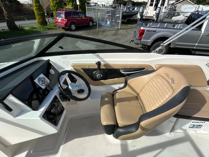 Slide: The Image of 2021 Sea Ray SPX 210 OB boat interior with steering wheel and tan seating. - 11
