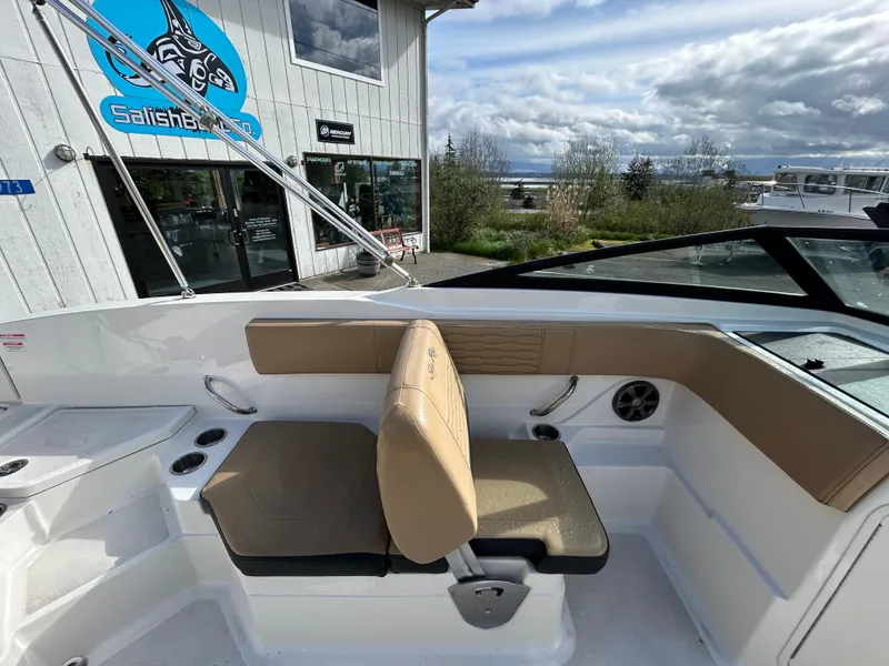 Slide: The Image of 2021 Sea Ray SPX 210 OB boat interior with tan seating, near a marine shop. - 5