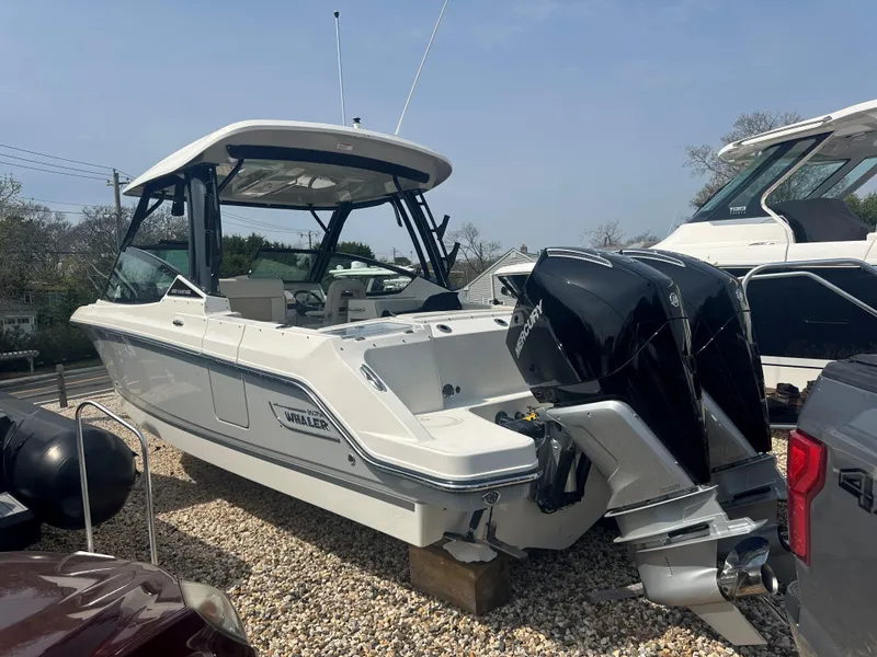 Slide: The Image of 2025 Boston Whaler 280 Vantage boat with dual engines, parked on gravel. - 2