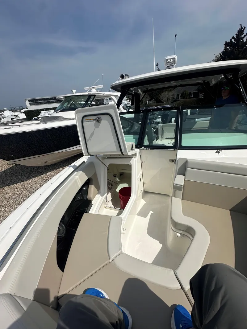 Slide: The Image of 2025 Boston Whaler 280 Vantage boat interior with open storage compartment, docked under clear sky. - 24