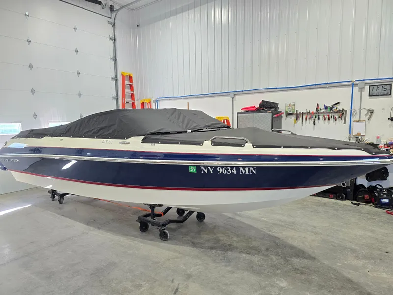 Slide: The Image of 2019 Larson LX 225 IO boat in a garage, covered and on a trailer. - 18