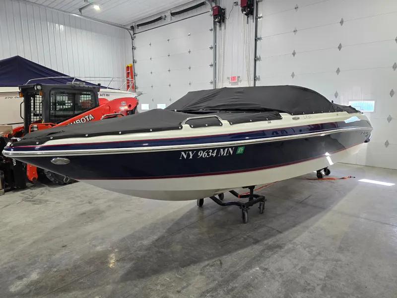 Slide: The Image of 2019 Larson LX 225 IO boat in a garage, covered and elevated on a stand. - 19