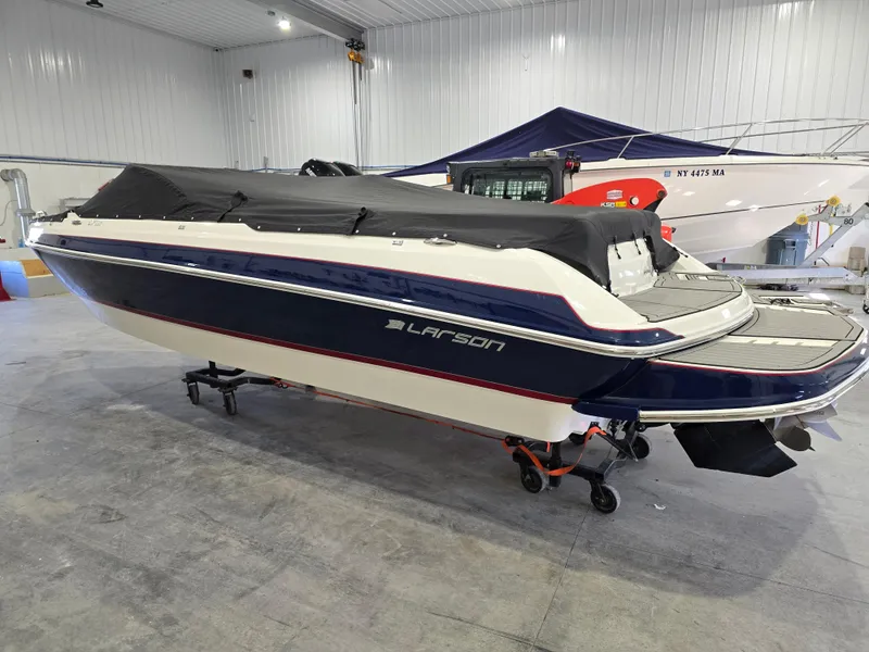 Slide: The Image of 2019 Larson LX 225 IO boat in indoor storage, covered and elevated on a dolly. - 20