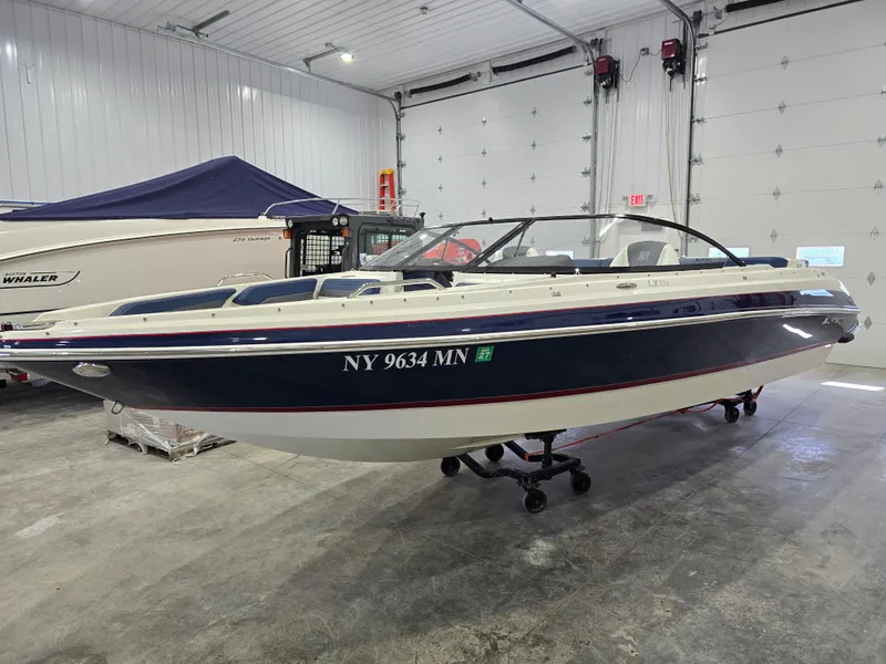 Slide: The Image of 2019 Larson LX 225 IO boat in indoor storage, blue and white exterior. - 22