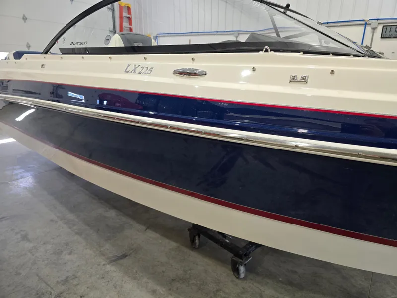 Slide: The Image of 2019 Larson LX 225 IO boat in a showroom, featuring sleek design and blue accents. - 25