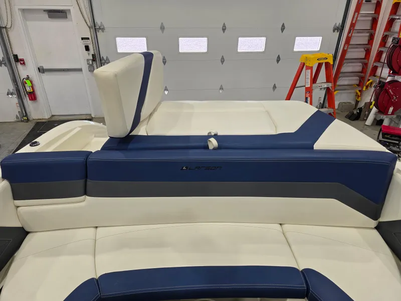 Slide: The Image of 2019 Larson LX 225 IO boat interior with blue and white seating in a garage setting. - 8