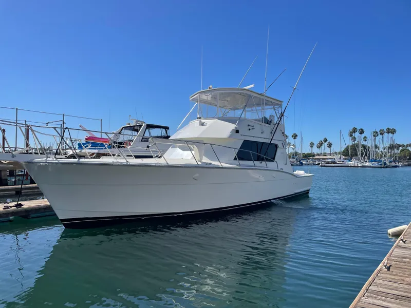 The Image of 1988 Hatteras 52 Convertible yacht docked in a marina under clear blue skies. - 0