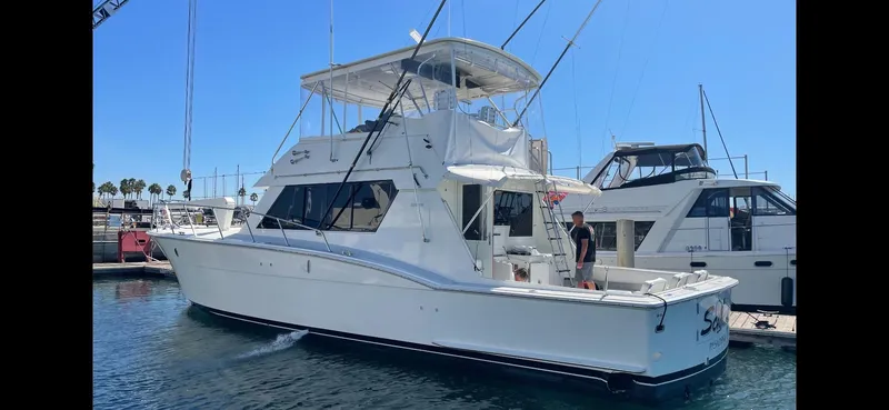 Slide: The Image of 1988 Hatteras 52 Convertible yacht docked in marina under clear blue sky. - 2