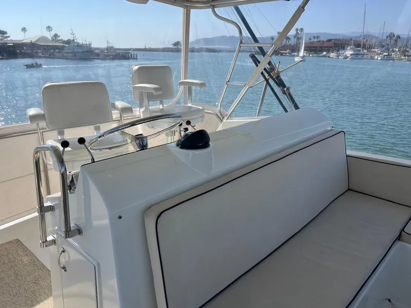 Slide: The Image of 1988 Hatteras 52 Convertible yacht helm with seating, overlooking a serene marina. - 36